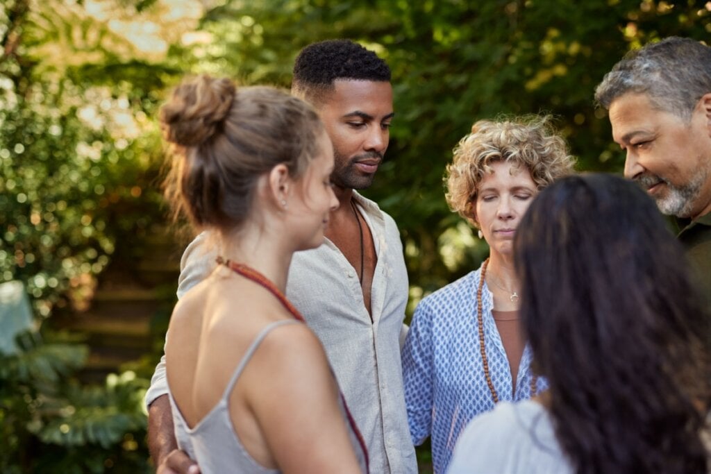 homens e mulheres reunidos em cÃ­rculo e com os olhos fechados