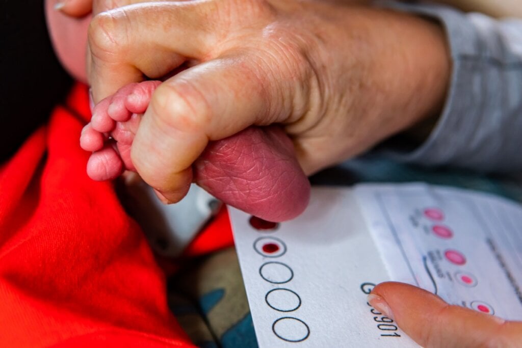 Imagem de uma enfermeira fazendo a coleta de sangue do calcanhar de um recÃ©m-nascido para realizaÃ§Ã£o do teste do pezinho