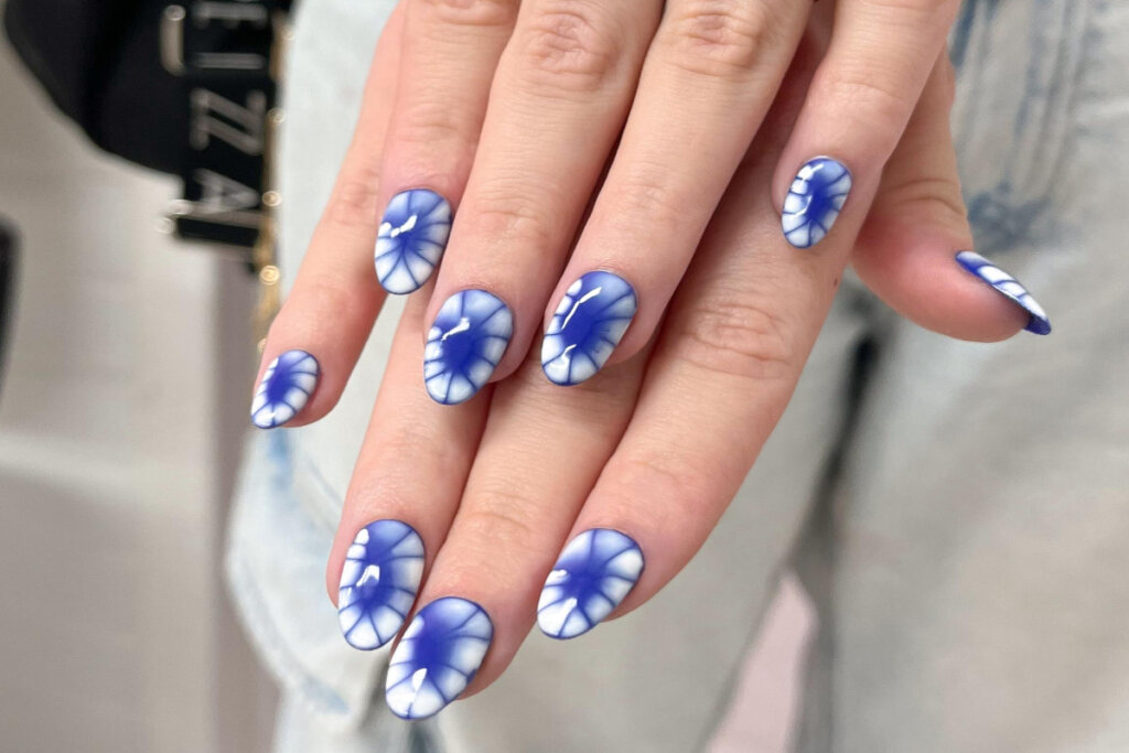 duas mÃ£os com unhas em tons de azul e branco