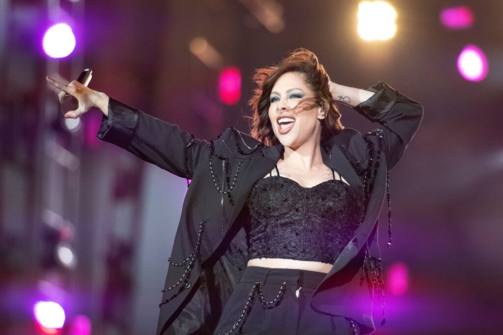 Pitty em cima de um palco usando roupa preta e cantando