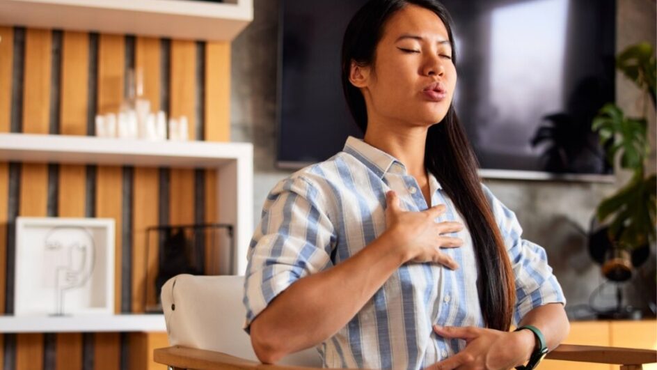 Mulher sentada com as mãos no peito fazendo exercício de respiração