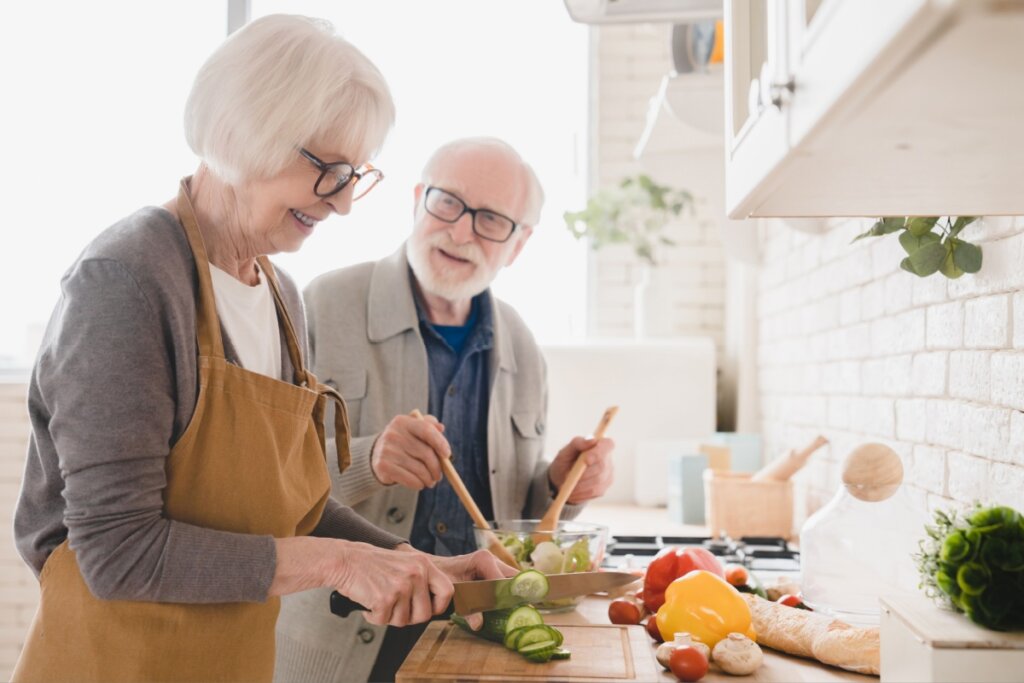 Mulher e homem idosos em uma cozinha cozinhando