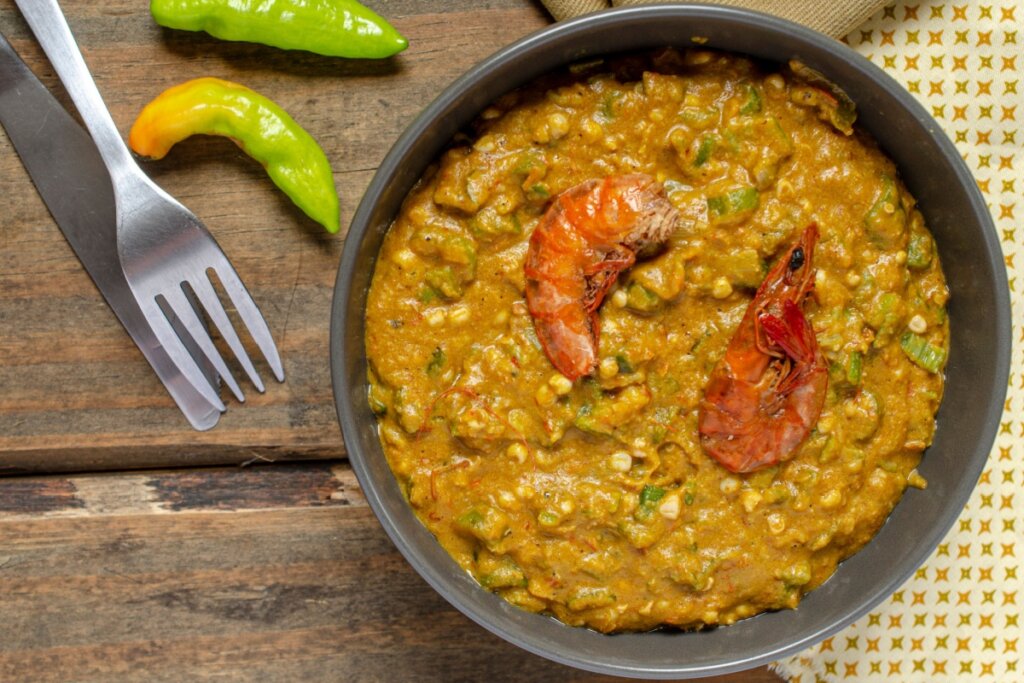 prato preto com caruru de quiabo alaranjado com dois camarÃµes em cima