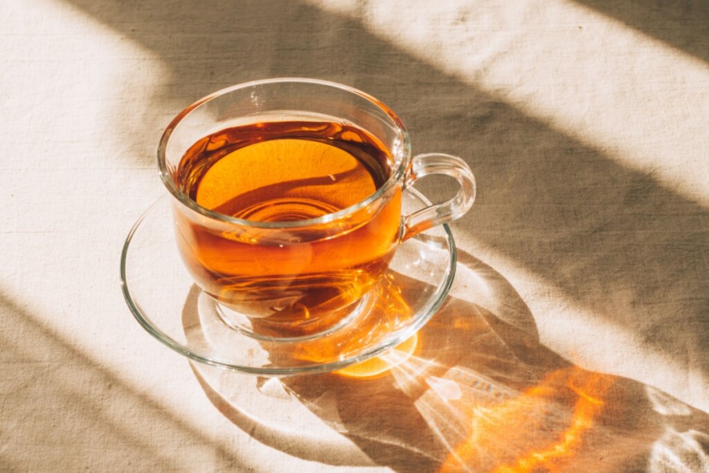 XÃcara de vidro com chá em cima de um pano bege claro