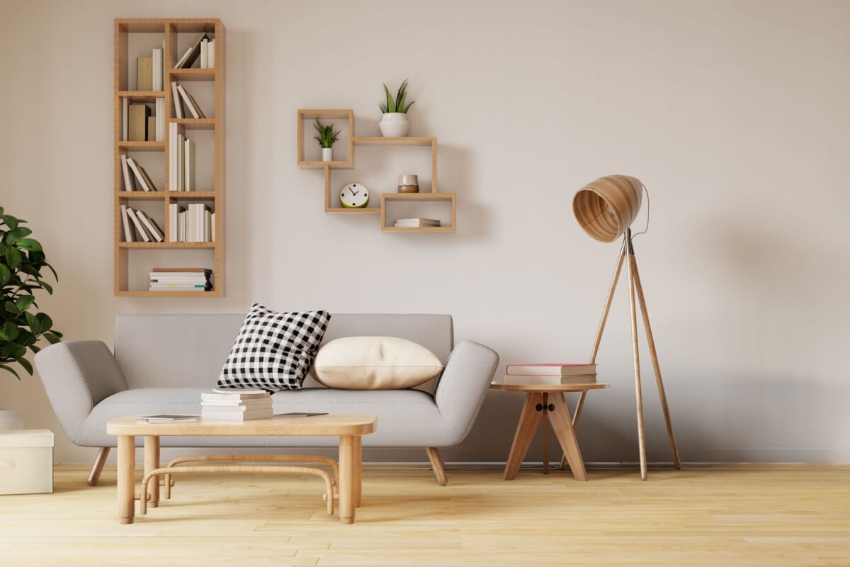Sala de estar com parede branca, sofÃ¡ cinza, mesa de centro e alguns itens de decoraÃ§Ã£o de madeira