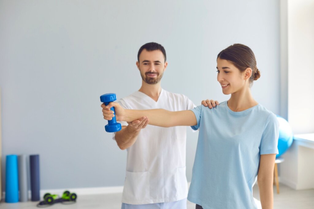 Mulher jovem fazendo exercÃ­cio com haltere leve sob orientaÃ§Ã£o de um profissional de saÃºde