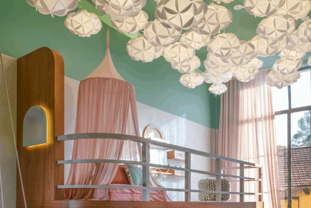 Quarto infantil com mezanino em madeira, e luminárias em forma de nuvens no teto, com parte da parede branca e verde e teto verde, com cortinas rosa e uma janela grande