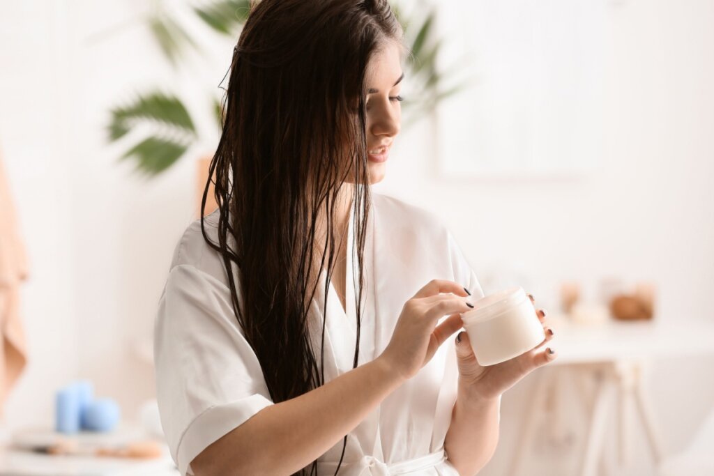 Mulher com o cabelo liso longo, cuidando do cabelo apÃ³s o banho, usando um roupÃ£o branco