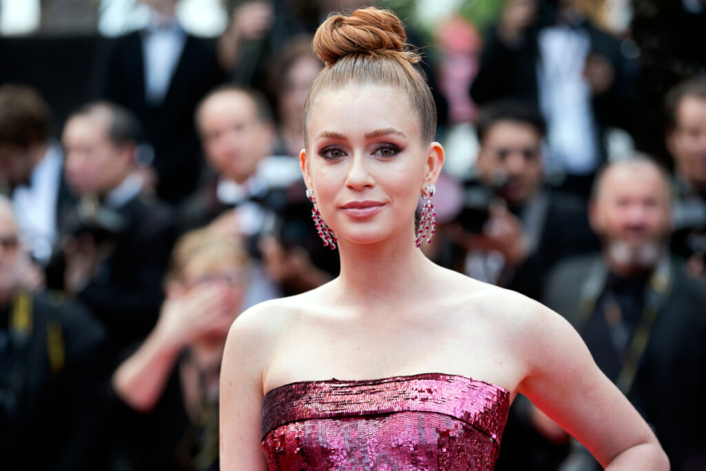 Mulher com o cabelo ruivo preso em coque usando vestido roxo brilhante