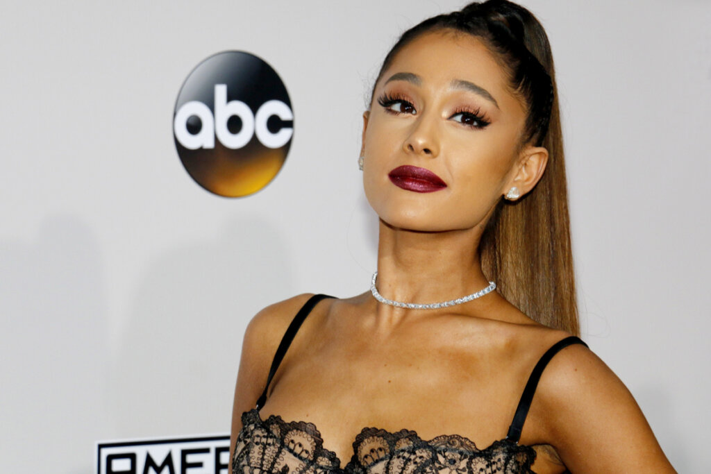 Mulher com cabelo liso amarrado em rabo de cavalo, usando top de alcinhas e renda preto posando para foto