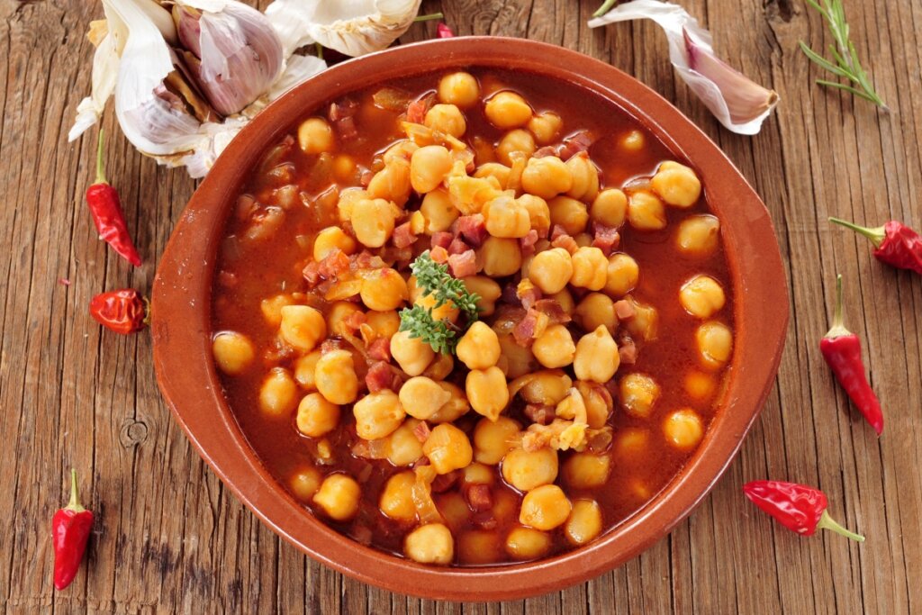 Panela de barro marrom com ensopado de grão-de-bico com bacon