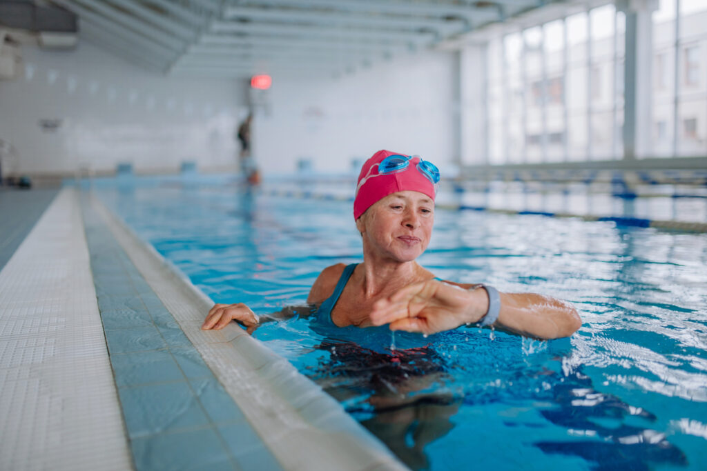 Mulher dentro de uma piscina olhando para um relógio