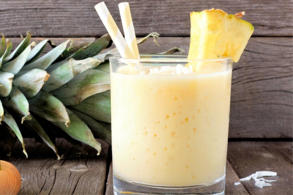 Copo de vidro com vitamian de abacaxi decorado com um pedaÃ§o de abacaxi