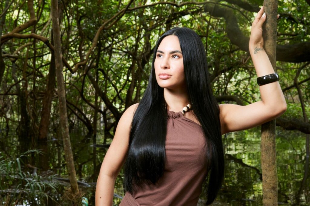 Influenciadora Isabelle Nogueira com cabelo preto longo posando para foto em uma floresta