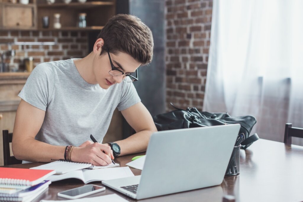 Jovem concentrado estudando em frente a um notebook e sentando