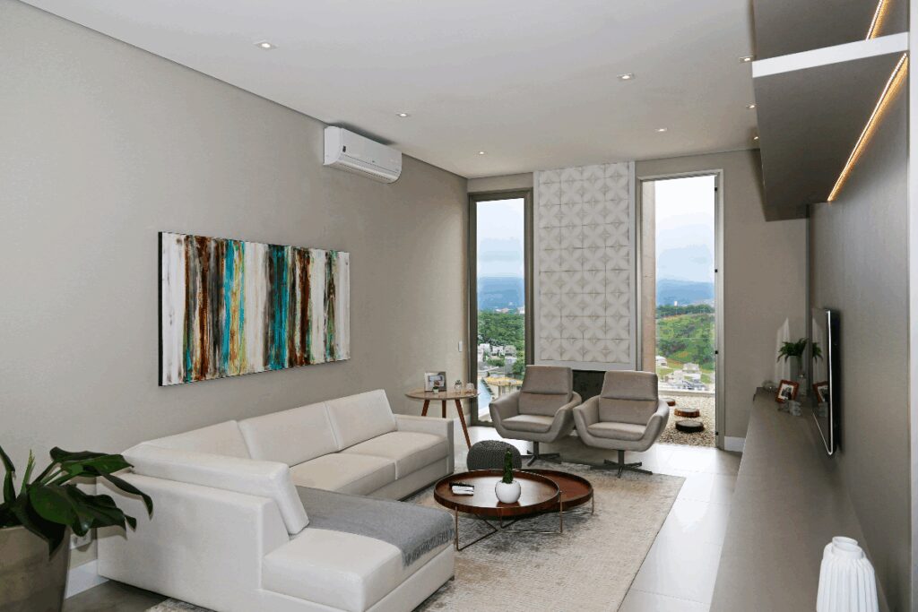 Sala de apartamento com sofÃ¡ branco, com quadro colorido na parede e mesa de centro em madeira, com forro branco com luminÃ¡rias