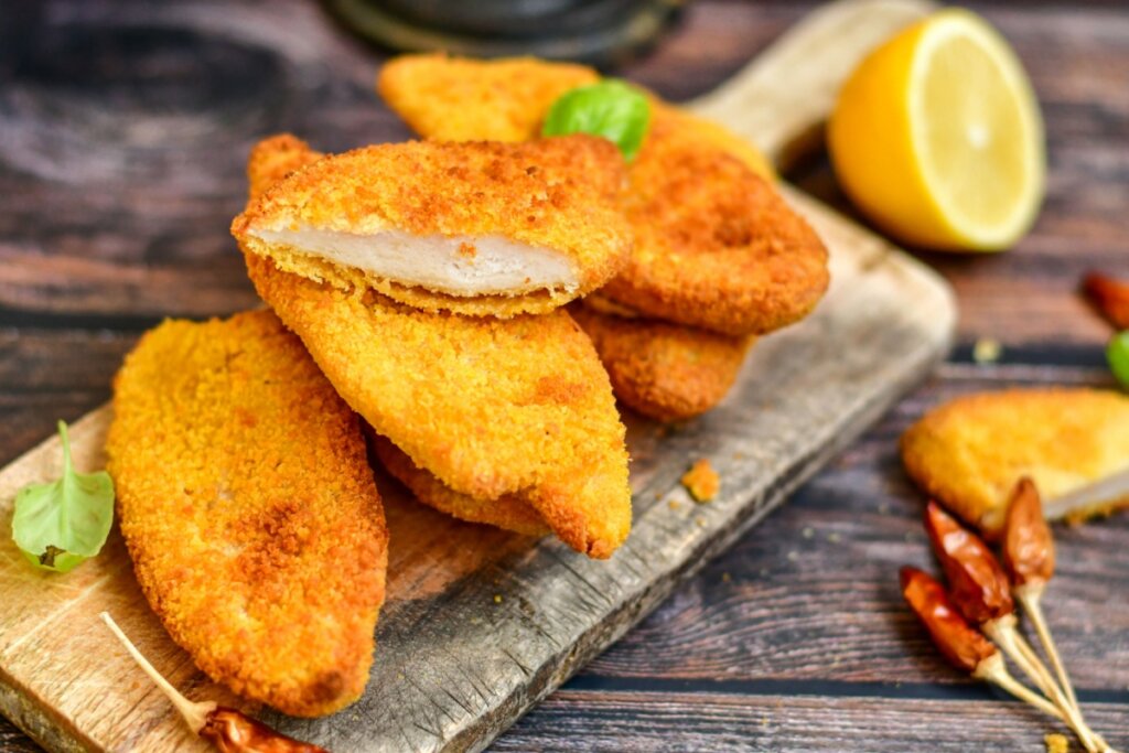 cinco filés de frango à milanesa dourados e crocantes em cima de tábua