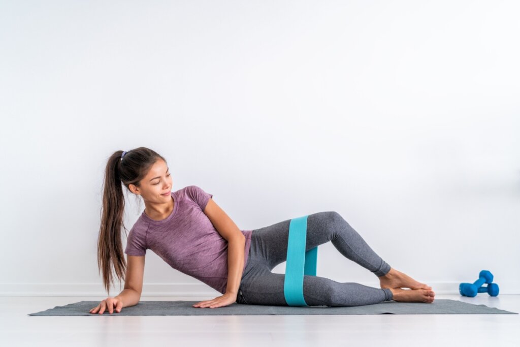 Mulher deitada com um mini band acima do joelho fazendo exerc&Atilde;&shy;cio de gl&Atilde;&ordm;teo m&Atilde;&copy;dio