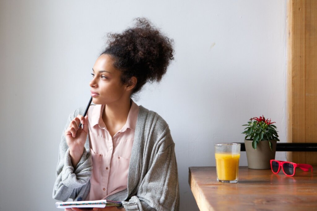 Mulher sentada pensando e segurando uma caneta