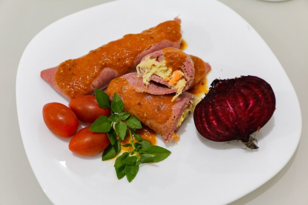 Duas panquecas de beterraba com frango em cima de um prato branco com beterraba e três tomates-cereja