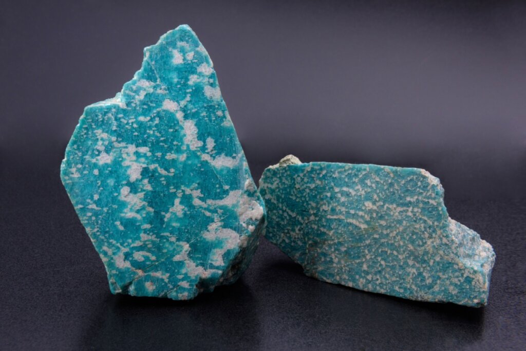 Duas pedras amazonitas na cor azul-claro sobre um fundo preto