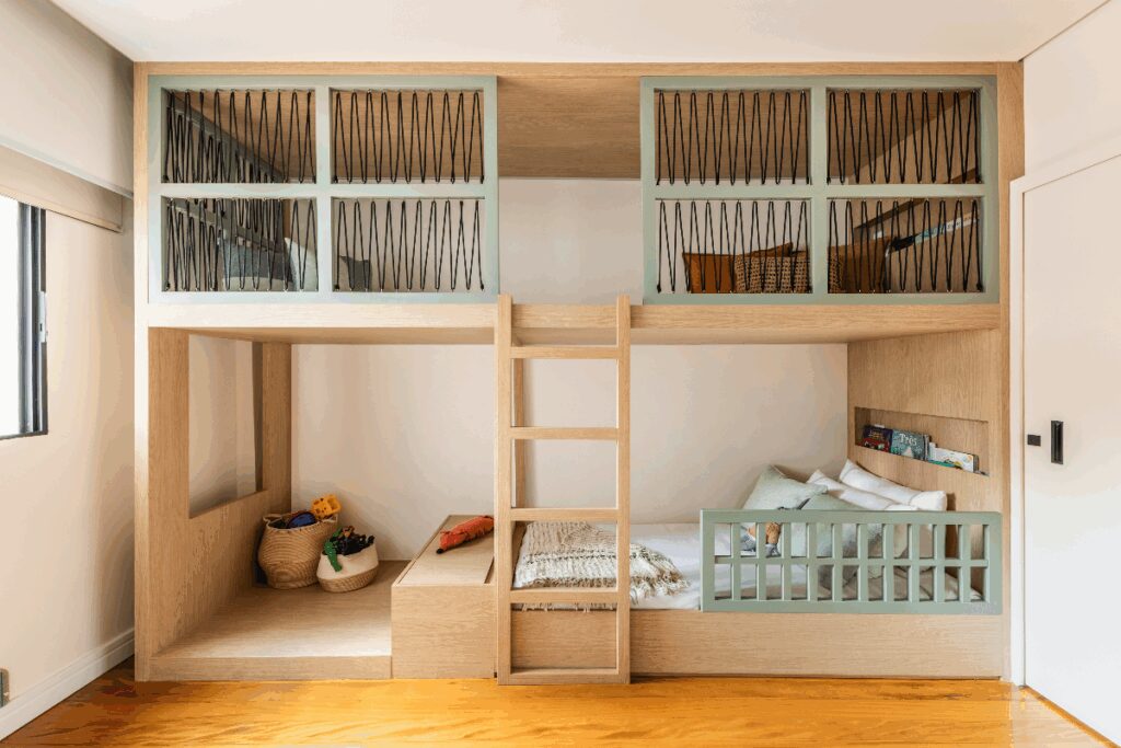 Quarto com cama baixa em madeira em cor natural e verde e na parte de cima um espaço de leitura com almofadas coloridas