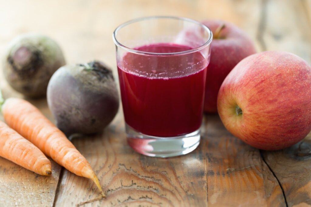 Suco de beterraba, ma&Atilde;&sect;&Atilde;&pound; e cenoura servido em copo de vidro com beterraba, ma&Atilde;&sect;&Atilde;&pound; e cenoura ao lado