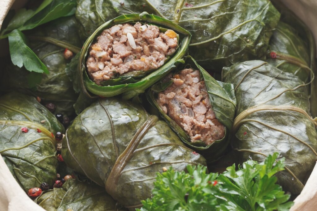 Charutinho de couve com carne e arroz servido em panela de barro