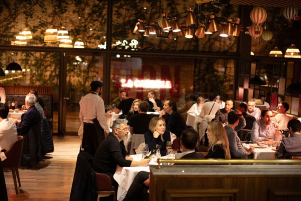 imagem de restaurante com pessoas sentadas em volta da mesa com luz amarelada