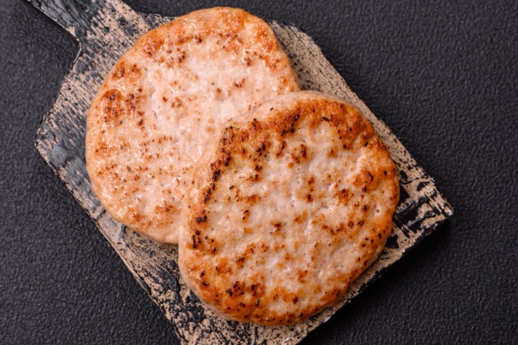 dois hambúrgueres assados e dourados em cima de tábua