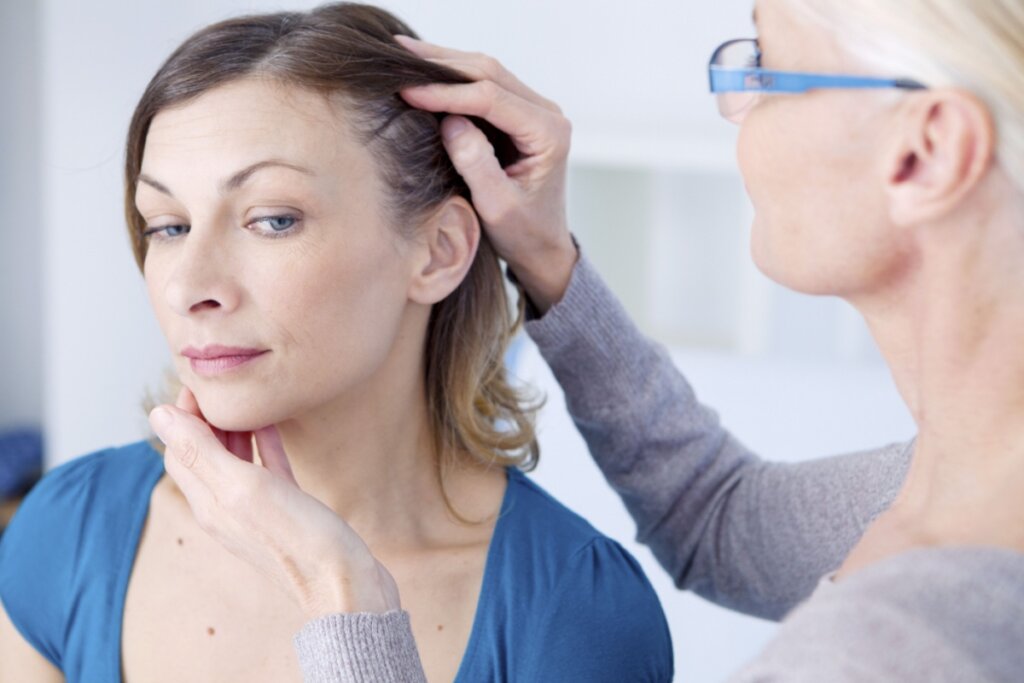 Mulher com cabelo curto, liso, usando camiseta azul, tendo o cabelo avaliado por mÃ©dica em consultÃ³rio