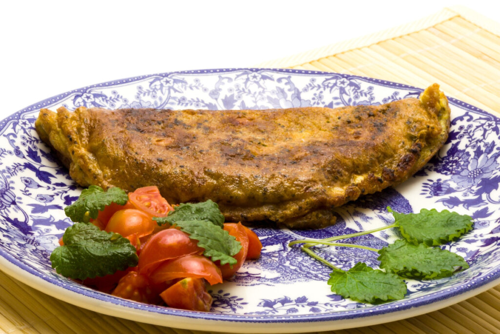 Omelete com chia em prato decorado azul e branco com tomate e tempero verde