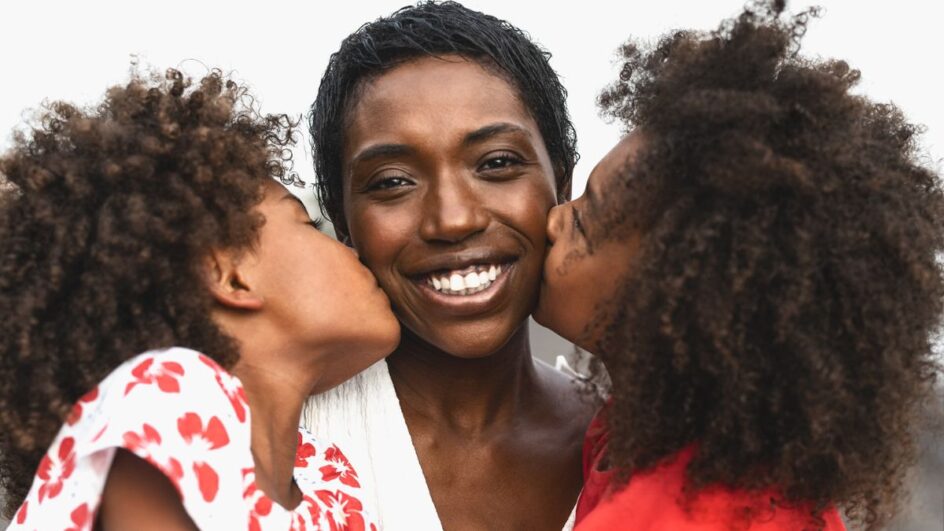 Mulher negra sorrindo com turbante colorido representando orgulho e ancestralidade para o Dia da Consciência Negra.