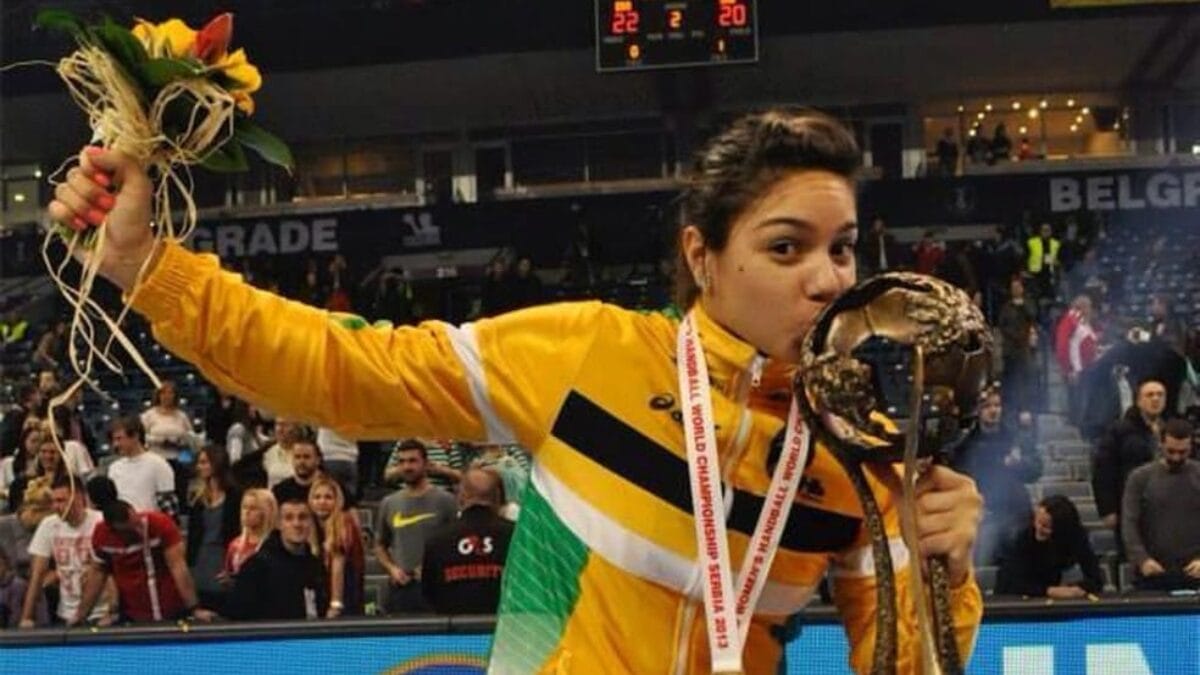 Hannah Nunes, campe&atilde; mundial de handebol, beijando trof&eacute;u e com flores na m&atilde;o