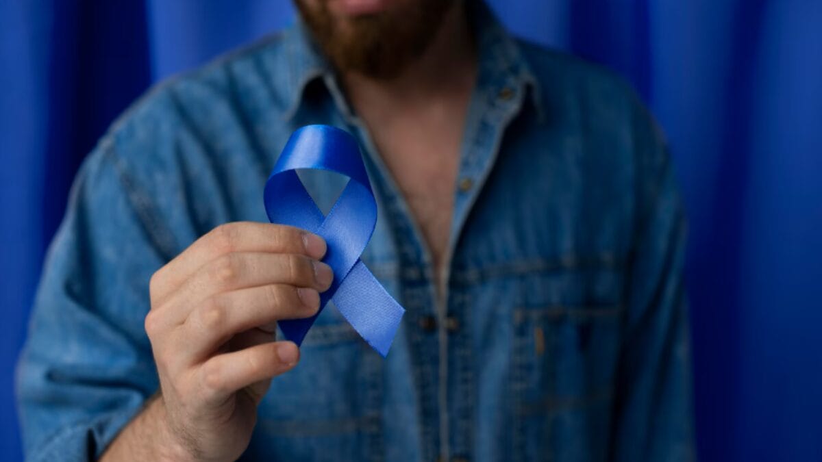 Homem segurando fita azul do Novembro Azul, campanha de combate ao câncer de próstata.