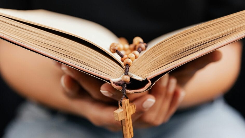 pessoa segurando bíblia com uma cruz