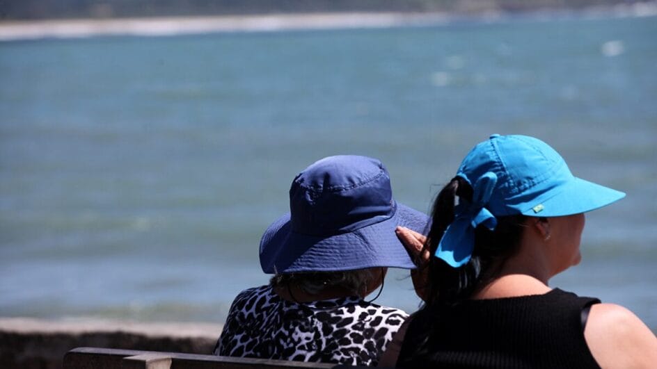 Duas mulheres usam chapéu em dia de sol e calor na Praia da Armação, em Florianópolis.