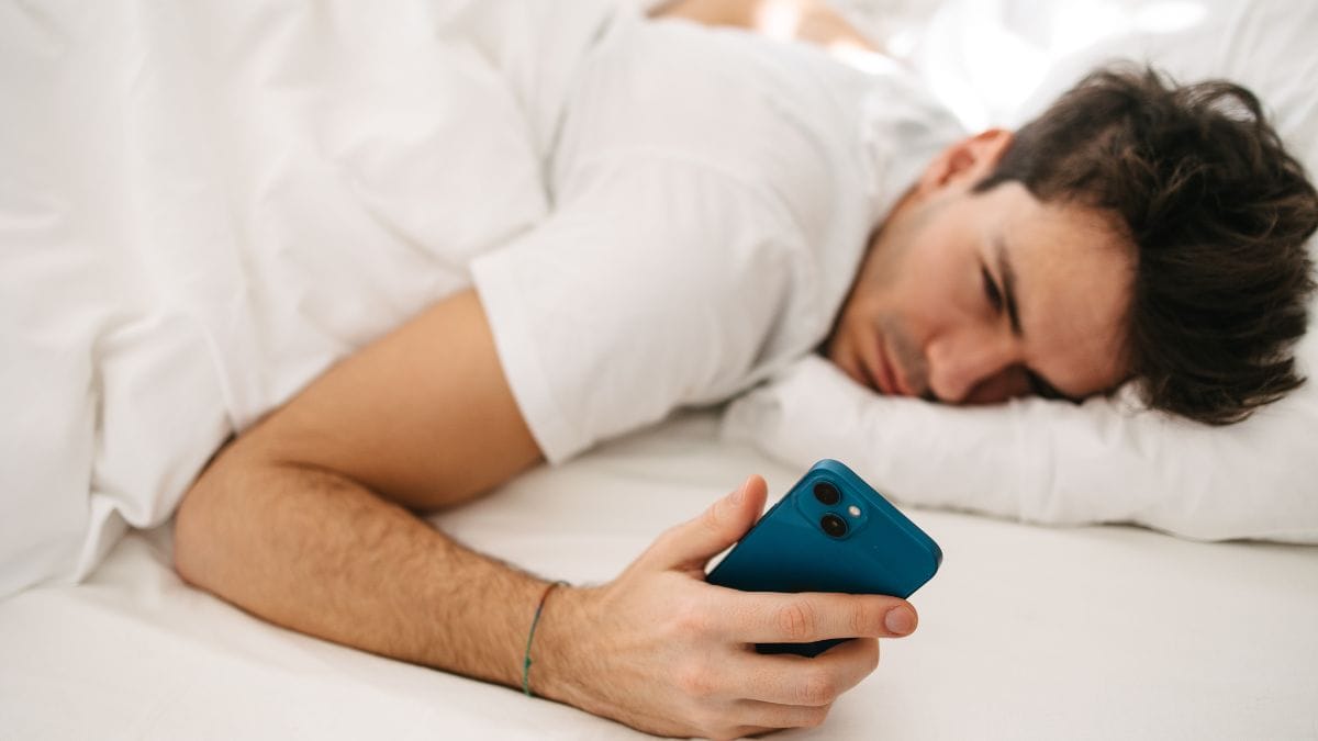 homem com celular na mão logo ao acordar