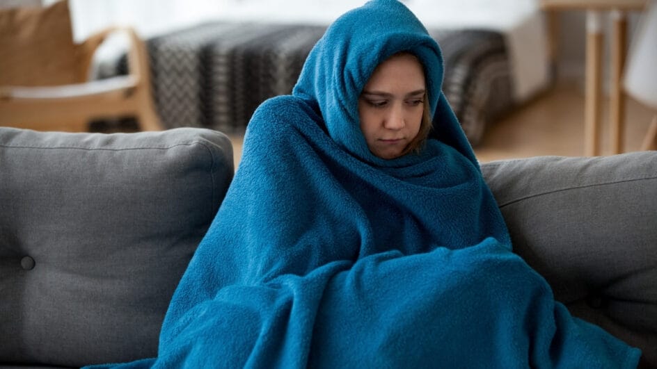 pessoa com muito frio enrolada em um cobertor azul
