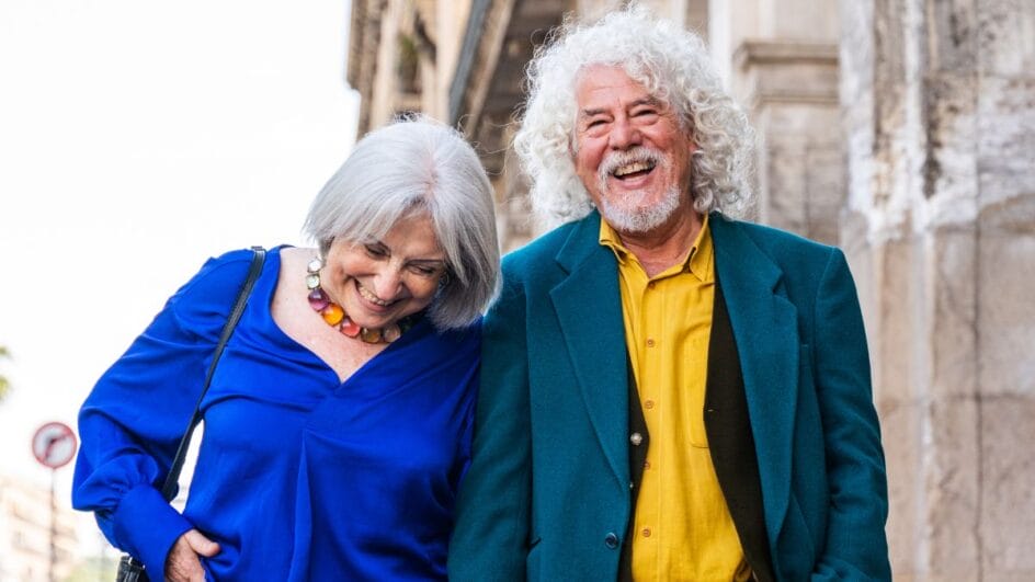 Idosos caminhando em parque ensolarado, prática associada ao retardo do Alzheimer segundo estudo.