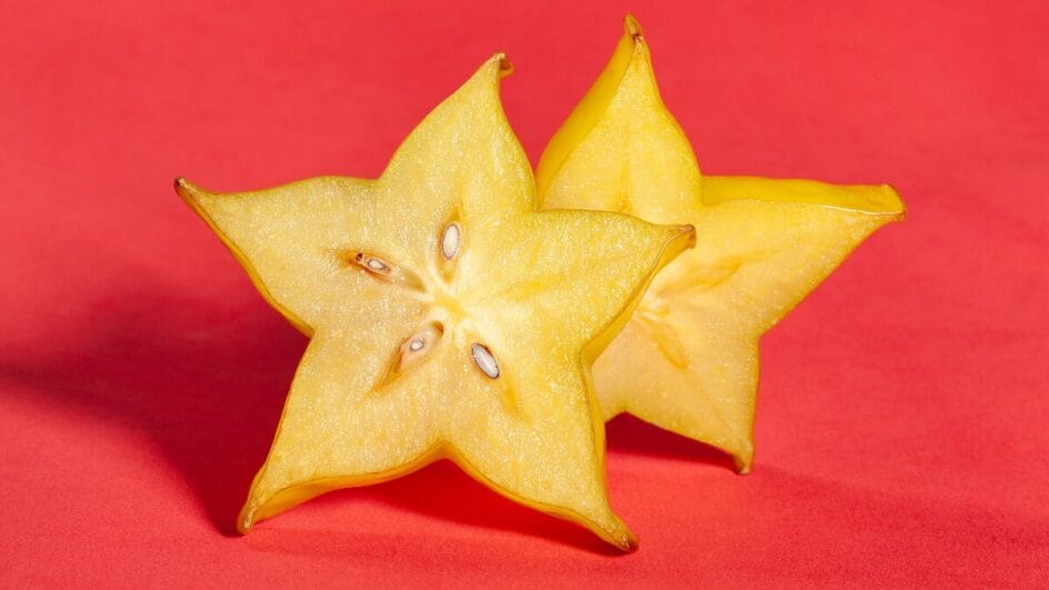 Close de uma carambola fatiada em uma superfície escura, ilustrando o alerta sobre seus riscos à saúde renal