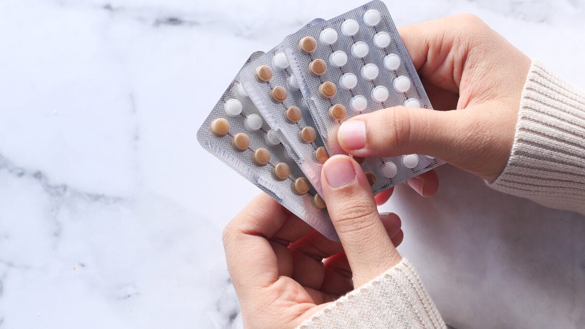 Mulher avaliando cartelas de pílulas anticoncepcionais