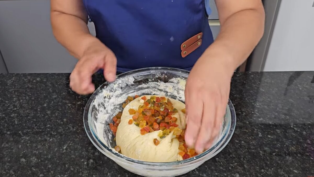 Mulher sovando massa em tigela com frutas cristalizadas