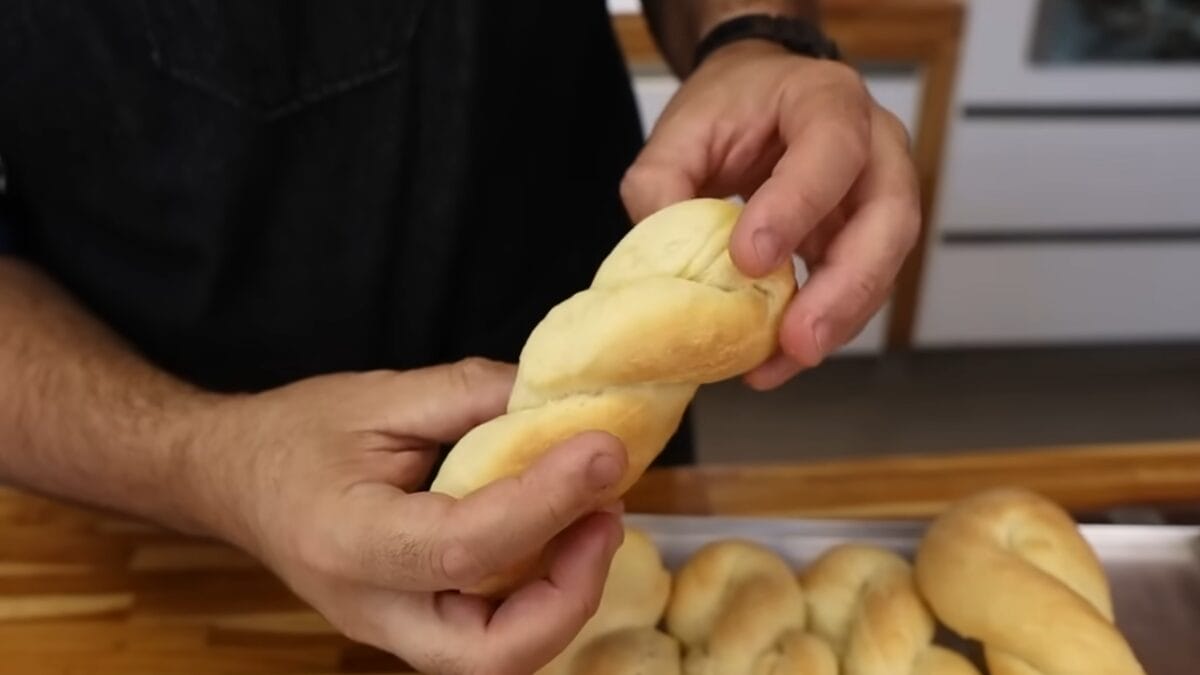 Homem mostra trancinha de coco, massa trançada assada