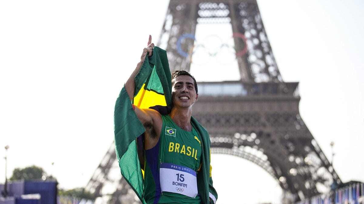 Caio Bonfim com a bandeira do Brasil nas costas e apontando para cima