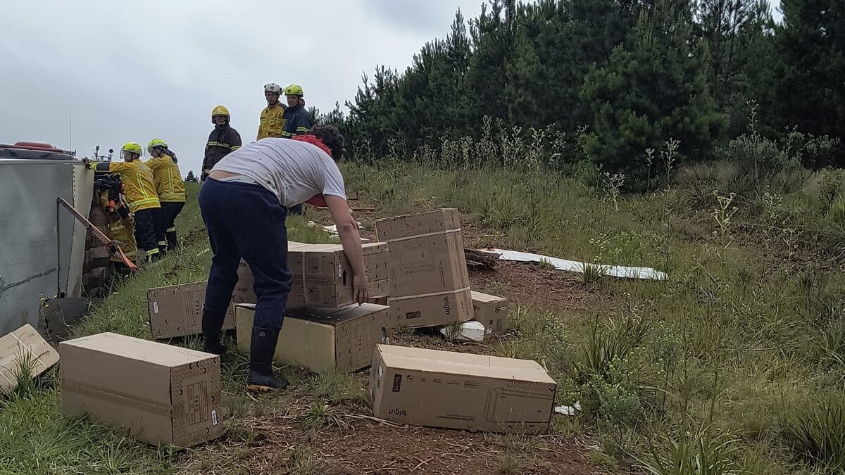 Moradores recolhendo caixas da carga espalhada após tombamento de caminhão na quarta-feira (10) na BR-153, em Água Doce.