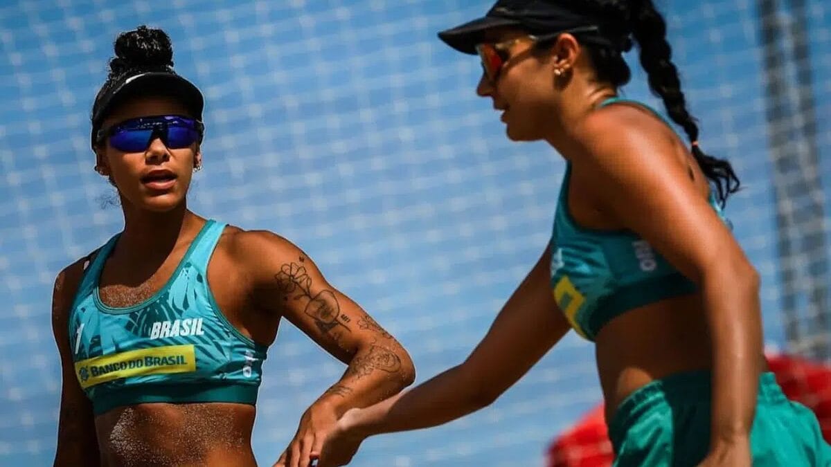 Thainara e Simonetti batendo as mãos em cumprimento durante jogo na areia