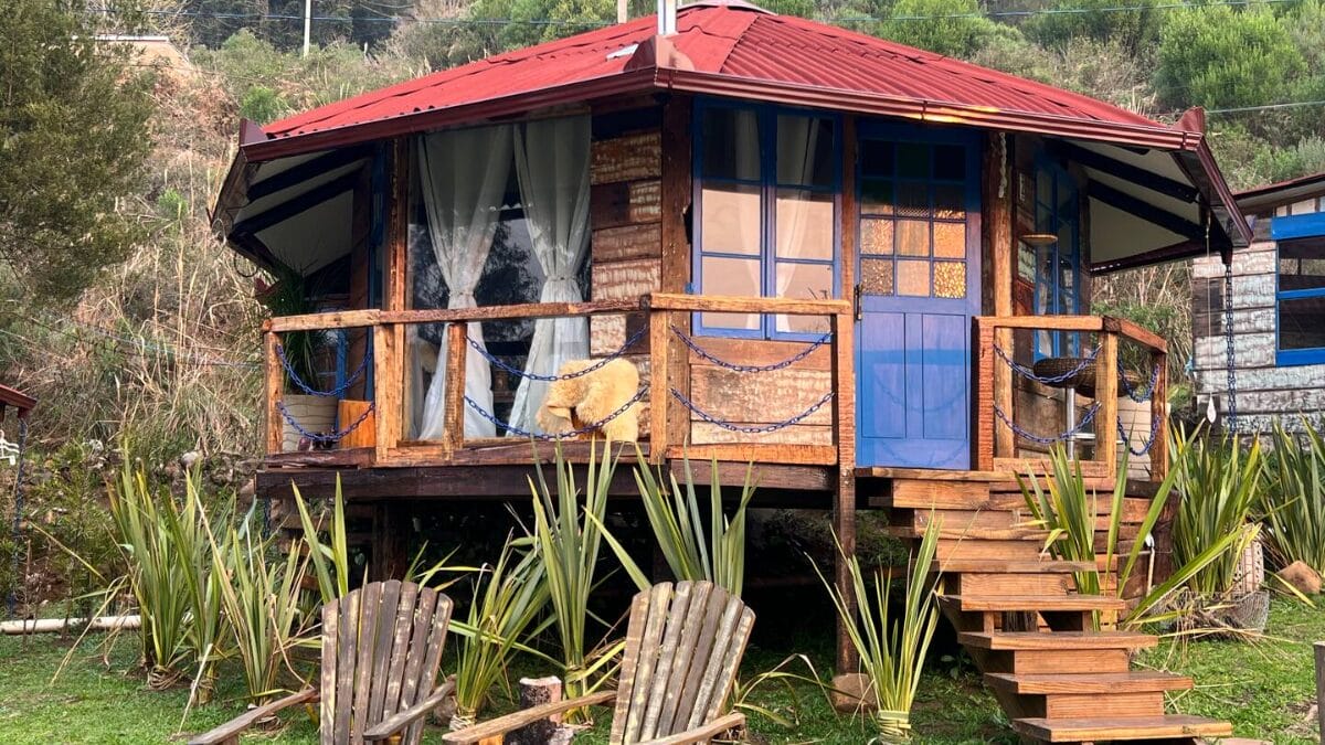 Cabana rústica com detalhes em azul e varanda com vista para a vegetação na serra catarinense.