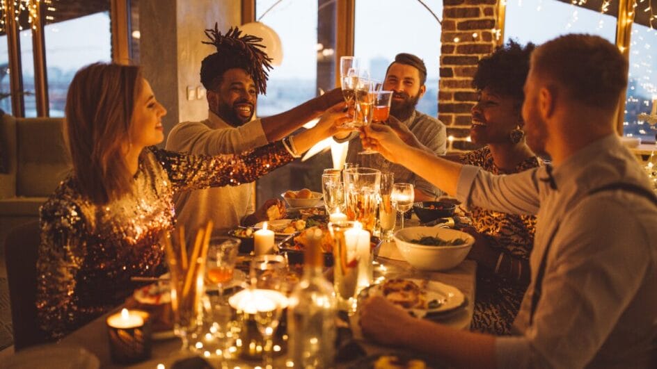 Pessoas reunidas em volta da mesa e brindando com felicidade