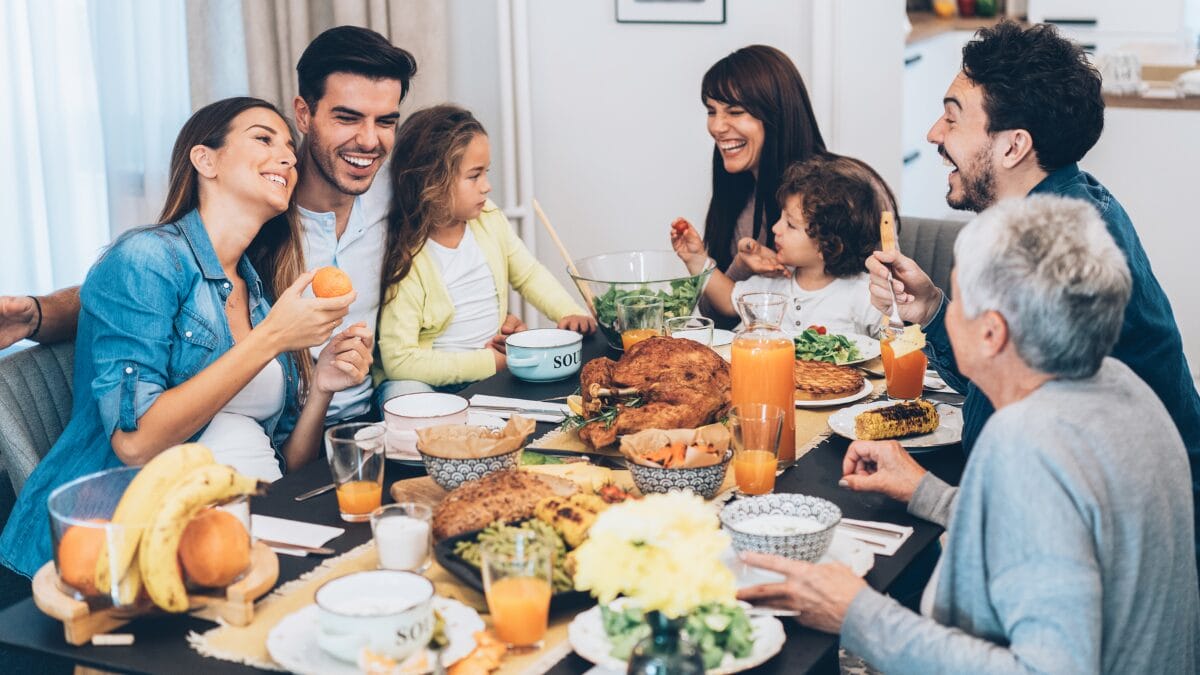 Família reunida à mesa em clima de festa, compartilhando ceia com pratos variados — cenário perfeito para receita de arroz com passas e alternativas para agradar a todos no fim de ano.